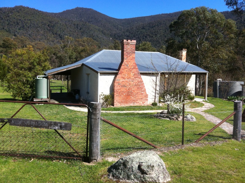 Nil Desperandum homestead. A small cottage with brick chimney and corrugated metal roof looks out over a hilly landscape. Photo: ACT Government 